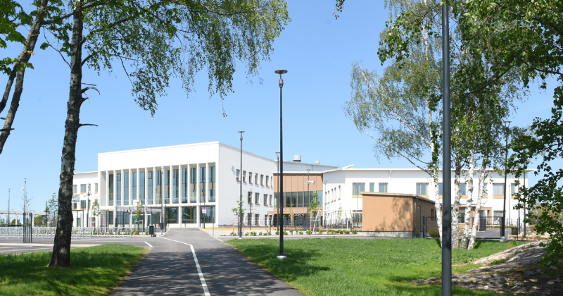 Uudenkaupungin monitoimijatalo Wintterin näyttävä julkisivu, etualalla kesäisiä koivun oksia.