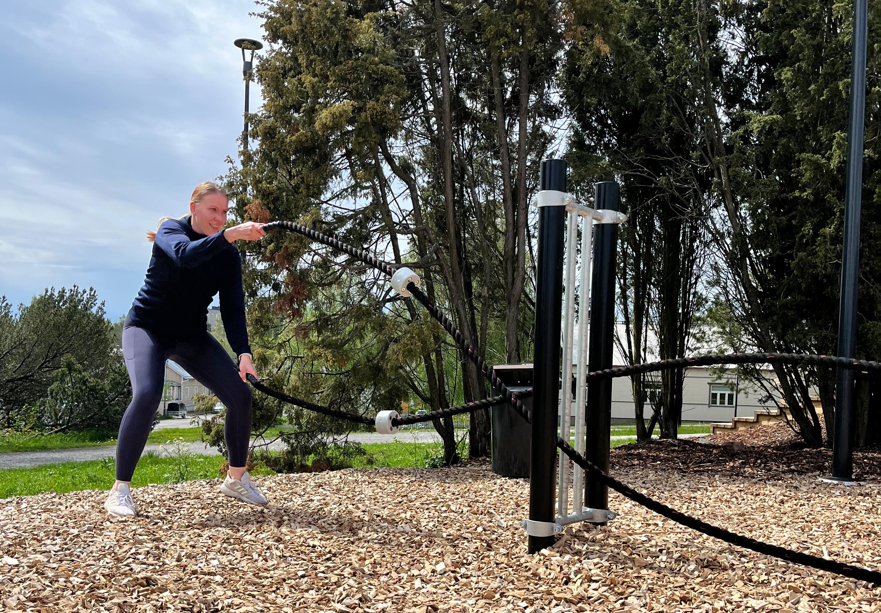 nainen treenaa ulkona voimaköysien kanssa