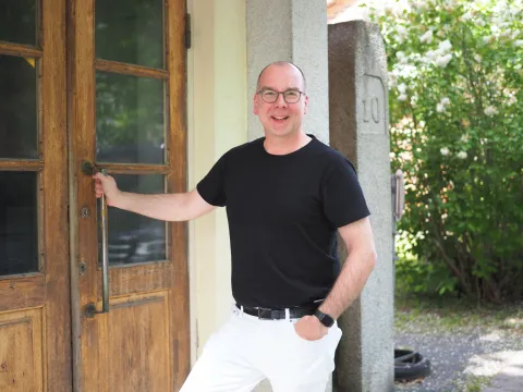 Vakka-Suomen musiikkiopiston rehtori Jussi Kauranen katsoo hymyillen kameraan ja pitää vanhanaikaisesta ulko-ovesta kiinni.