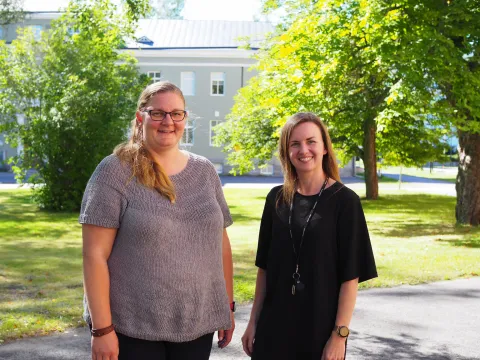 Jenni Leppänen ja Annina Kiiveri katsovat hymyillen kameraan, taustalla kesäinen maisema.